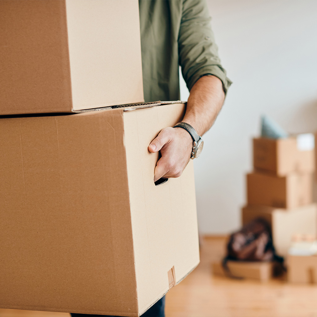Person carrying moving boxes into a new home